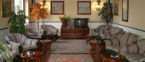 A traditional living room with striped sofas, a central rug, and a television.