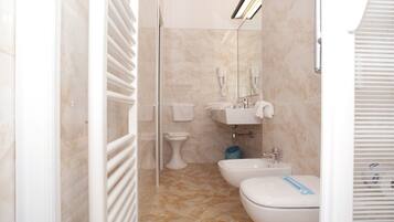 Ein modernes Badezimmer mit Duschkabine aus Glas, Toilette, Bidet und Waschbecken.