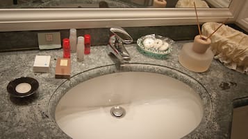 A bathroom sink with a mirror above it, a soap dispenser, a toothbrush holder, and a glass bowl with soap.