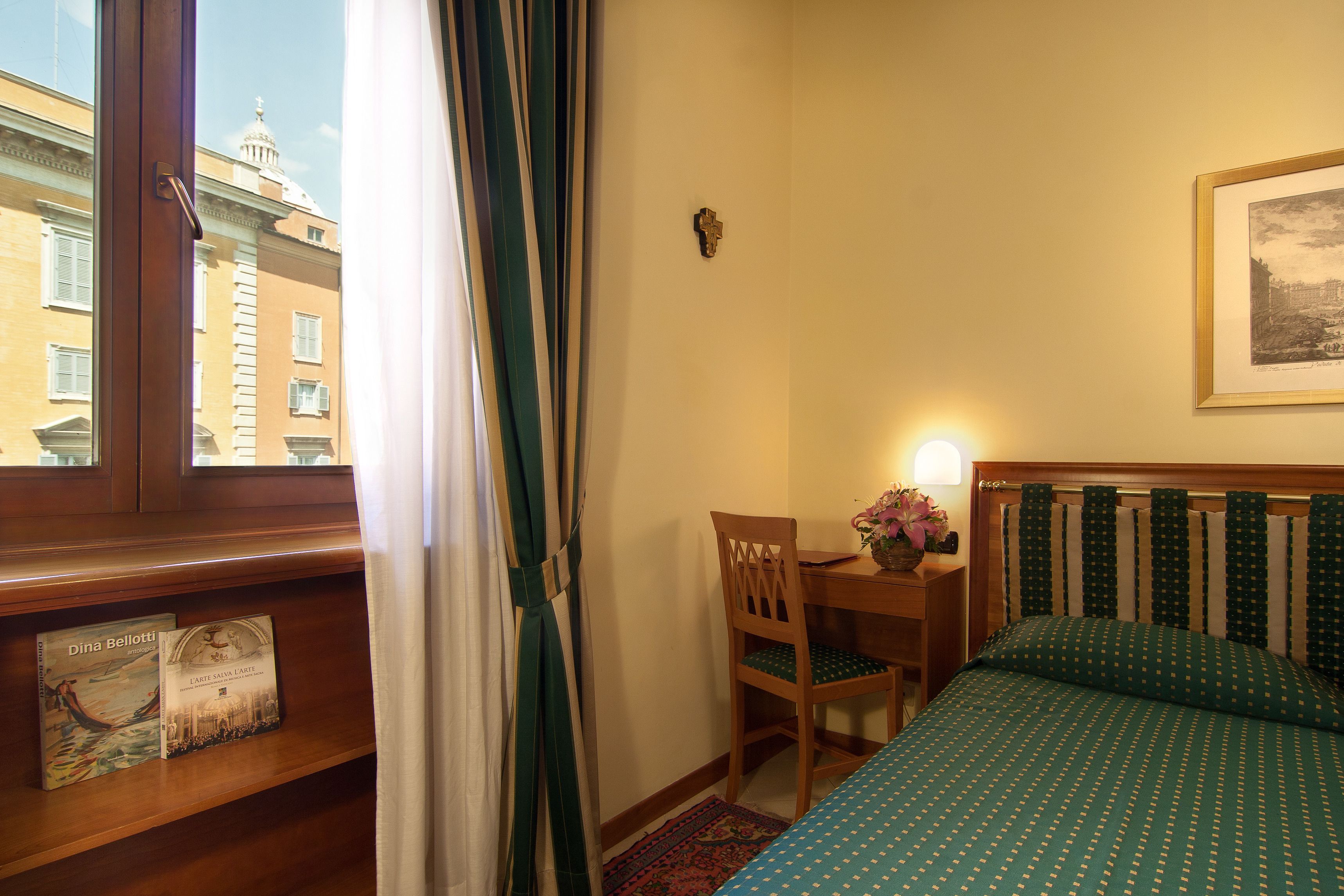 A hotel room with a bed, a desk, a chair, and a window with curtains.