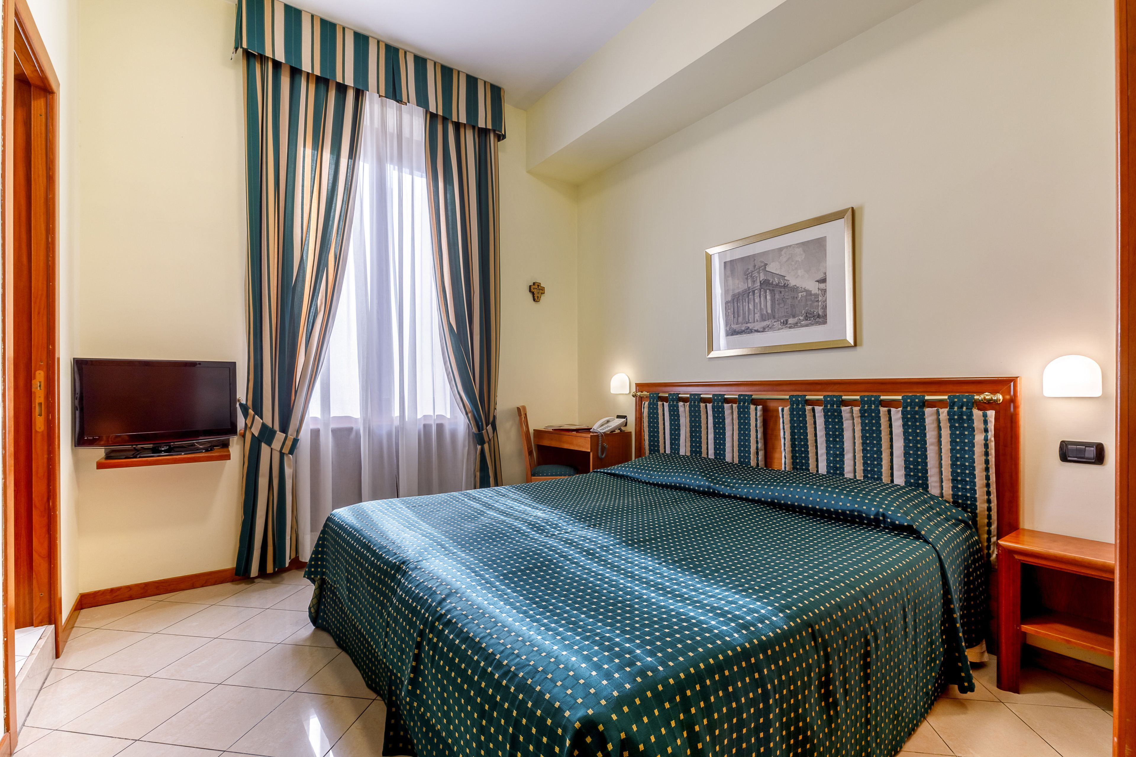 Une chambre d’hôtel avec un lit, une télévision, un bureau et une chaise.