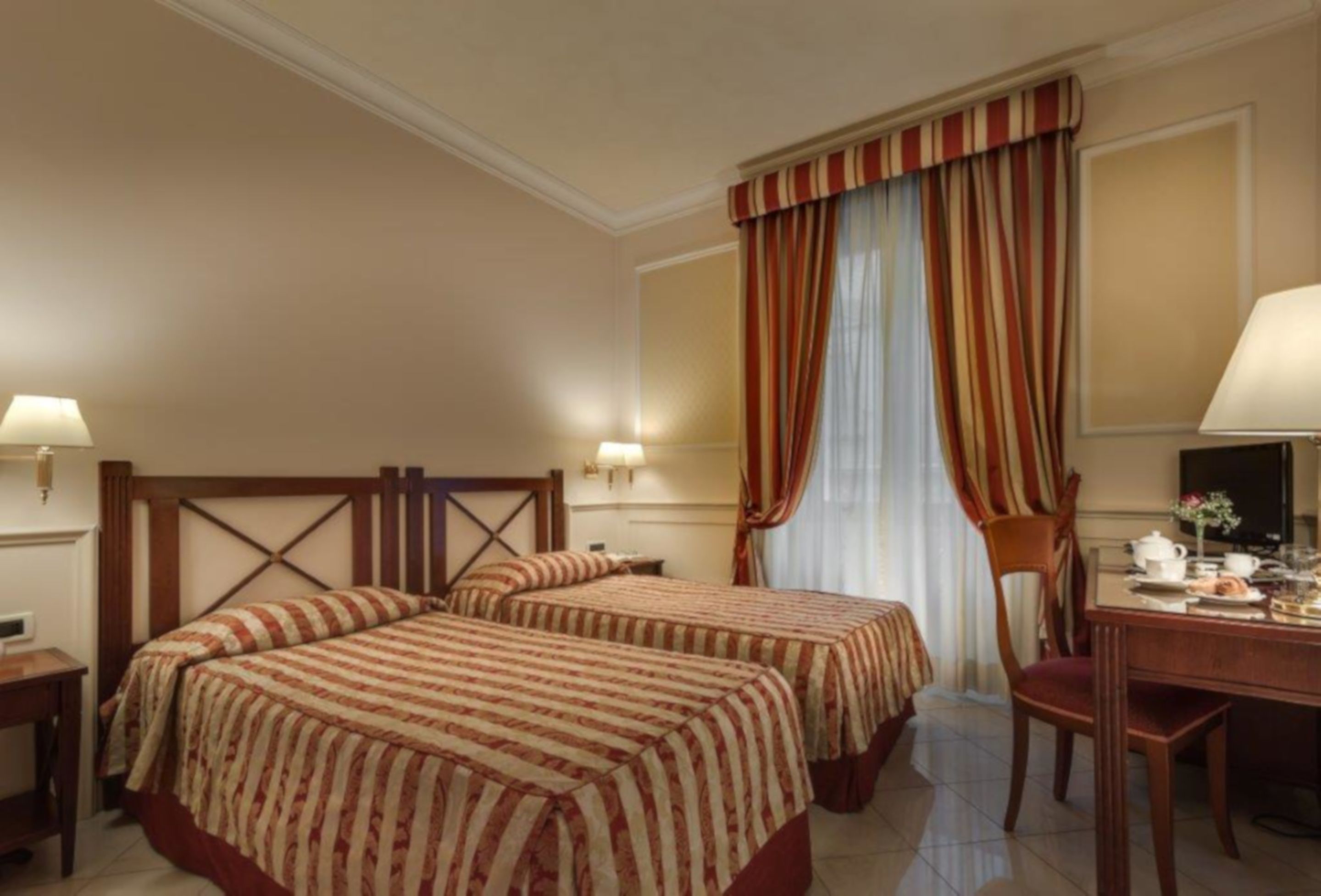 A hotel room with two beds, a desk, and a chair.