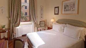 A hotel room with a large bed, a chair, a desk, and a window with curtains. - Residenza Paolo VI (Rome)