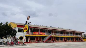 A motel with a two-story structure, a covered parking area, and a sign indicating it is open for the season.