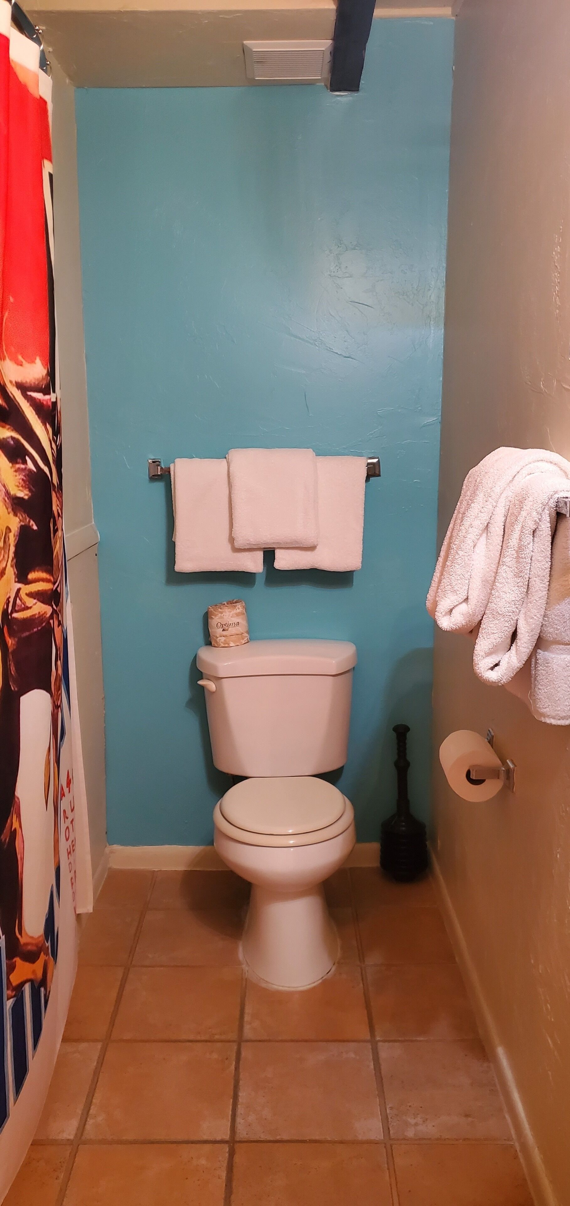 Een badkamer met een blauwe wand, toilet, twee witte handdoeken en een toiletrolhouder.