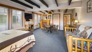 Une pièce confortable avec un lit, un canapé, une table à manger avec des chaises, un téléviseur et une fenêtre avec des rideaux.