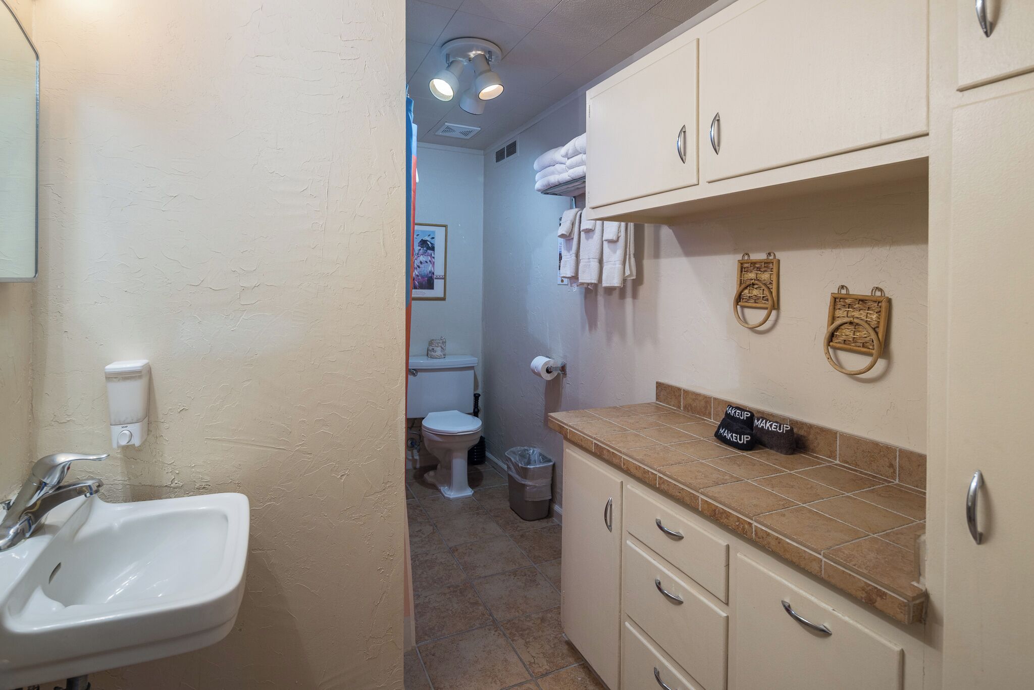 A bathroom with a sink, toilet, and storage cabinets.