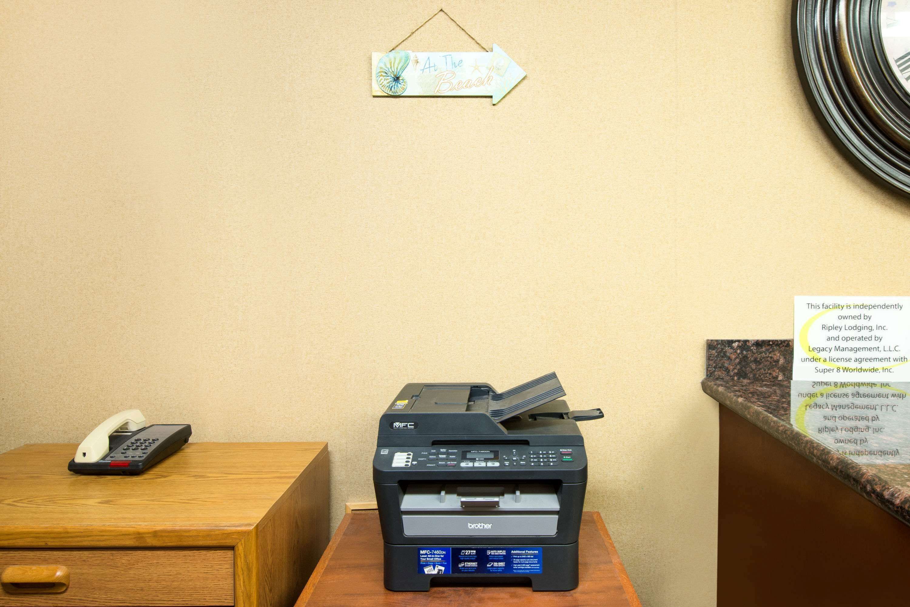 Een receptiebalie met een Brother-printer, een telefoon en een bordje met de tekst 'A The Beach'.