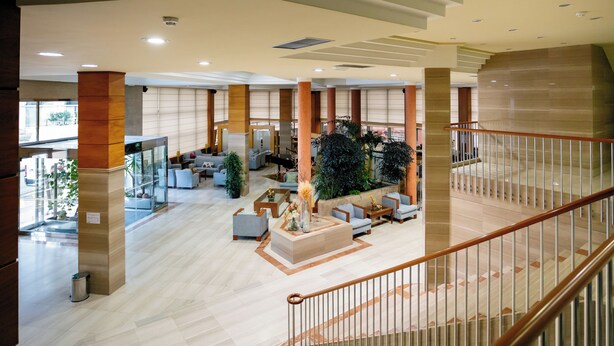 A spacious lobby with a central seating area, a staircase, and a view of the outside.