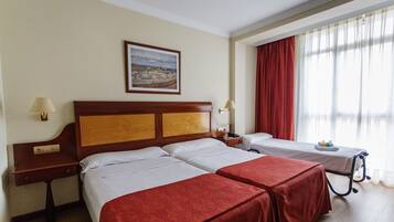 Habitación de hotel con dos camas, cabecera de madera, un cuadro en la pared y una ventana con cortinas.
