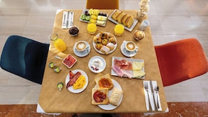 A breakfast table with various food items, drinks, and utensils.