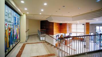 A spacious lobby with a marble floor, a staircase, and a large mural on the wall.