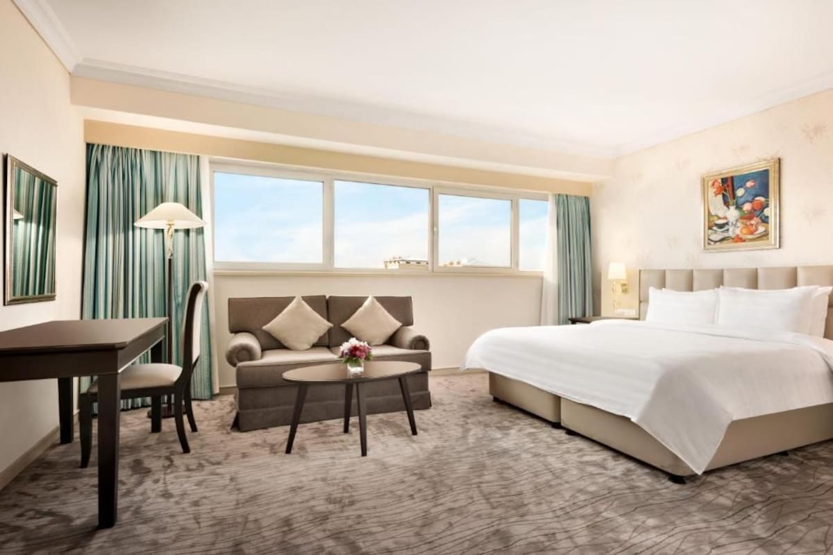 A hotel room with a bed, a sofa, a table, and a chair.