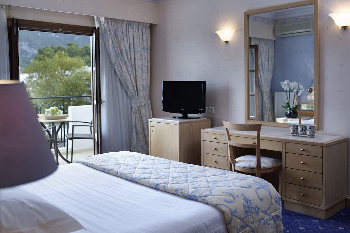 Ein Hotelzimmer mit einem Bett, einem Schreibtisch, einem Fernseher, einem Schminktisch und einem Spiegel.