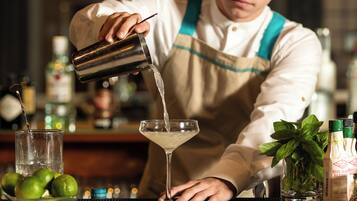 A bartender pouring a drink into a martini glass.