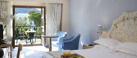 Une chambre d’hôtel avec un lit, une petite table, une chaise et un balcon donnant sur la mer.