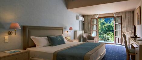 A hotel room with a large bed, a desk, a chair, and a view of the outdoors.