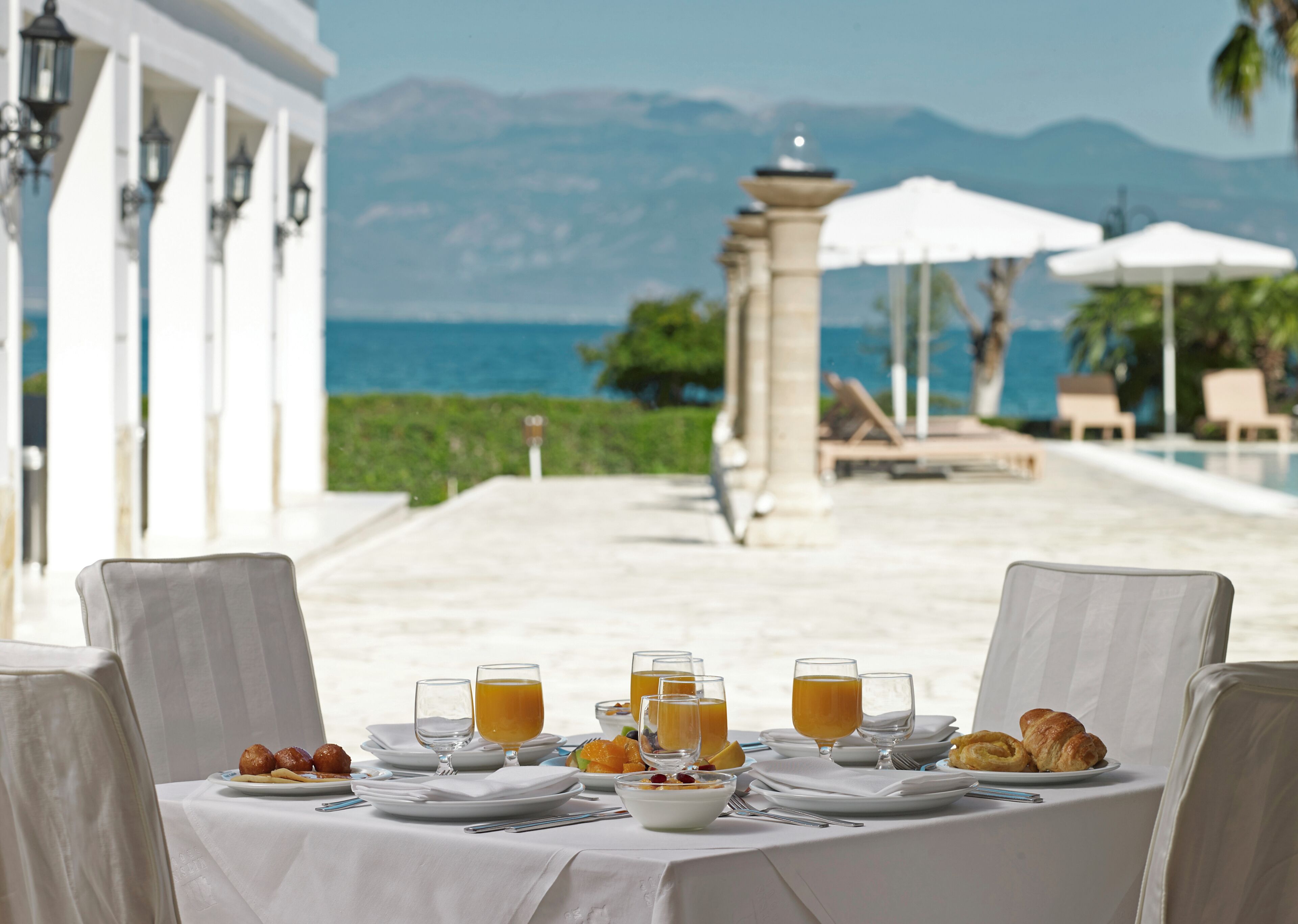A table set for breakfast with a view of the sea and mountains.