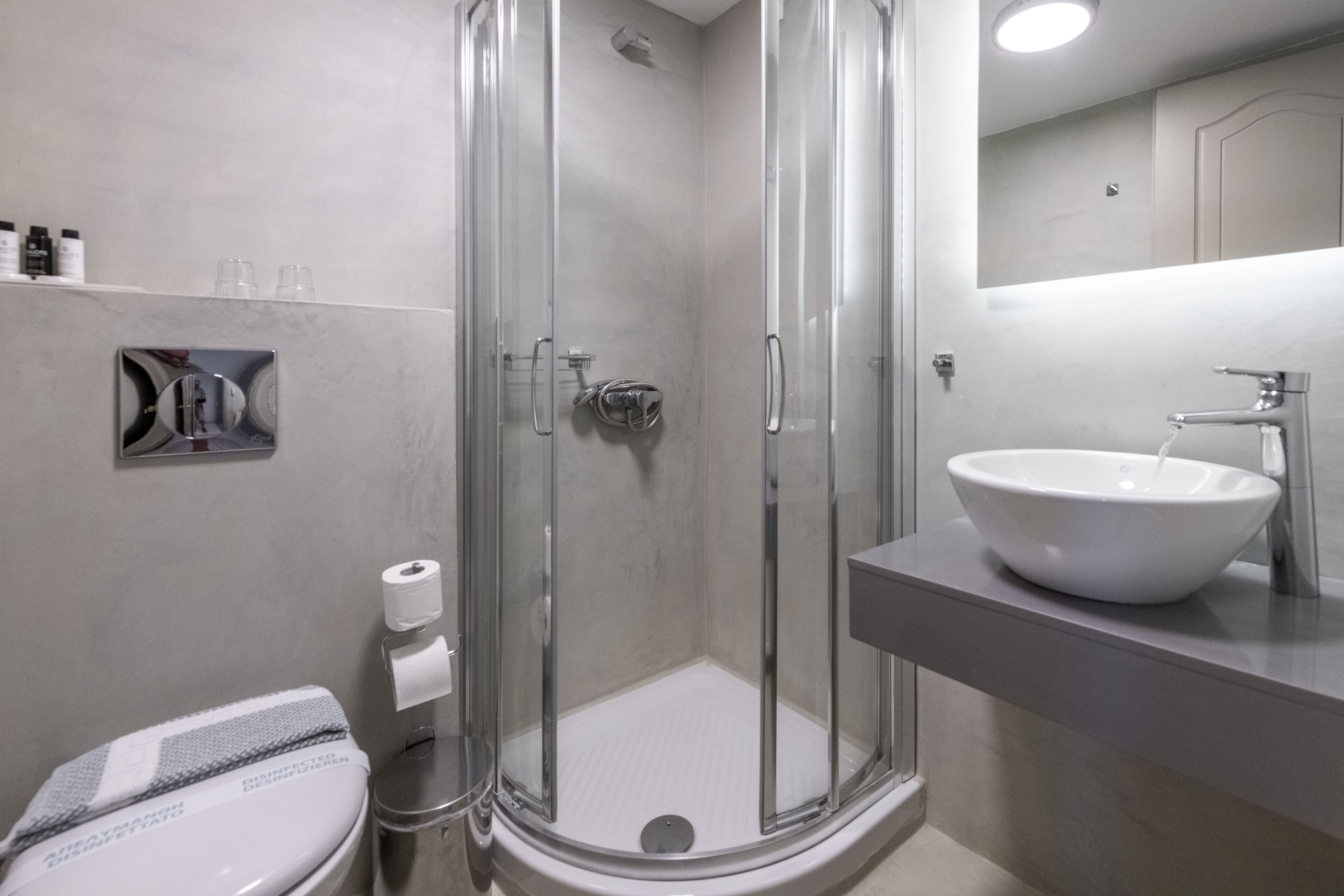 Un baño moderno con ducha envuelta en vidrio, un lavabo blanco y un inodoro.