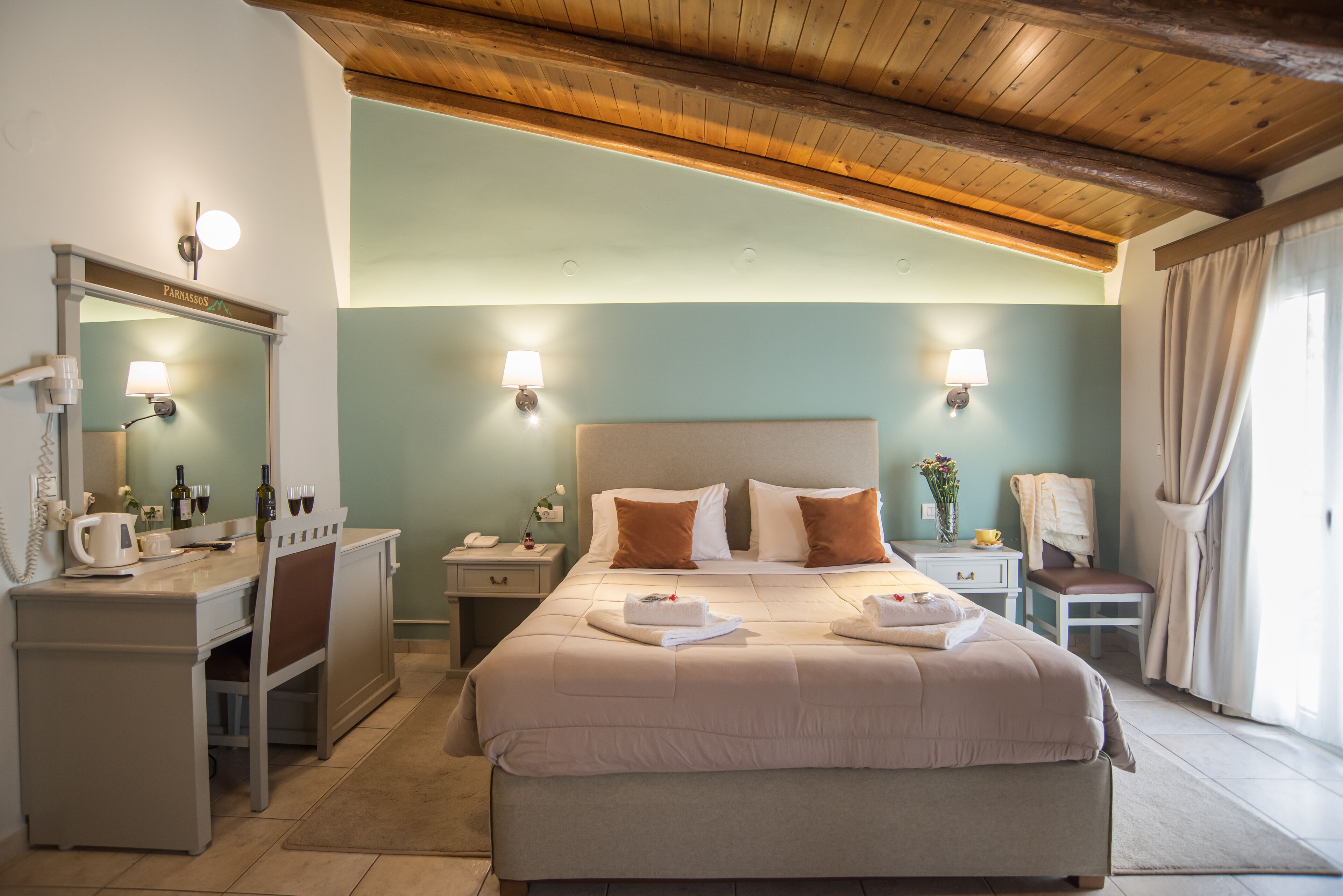 A well-lit bedroom with a large bed, bedside tables, a desk, and a mirror.