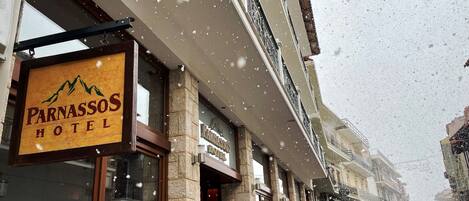 A hotel facade with a sign reading "Parnassos Hotel" and a stone exterior.