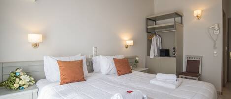 A hotel room with a large bed, white bedding, a nightstand with a lamp, a mirror, a robe, and a hairdryer.