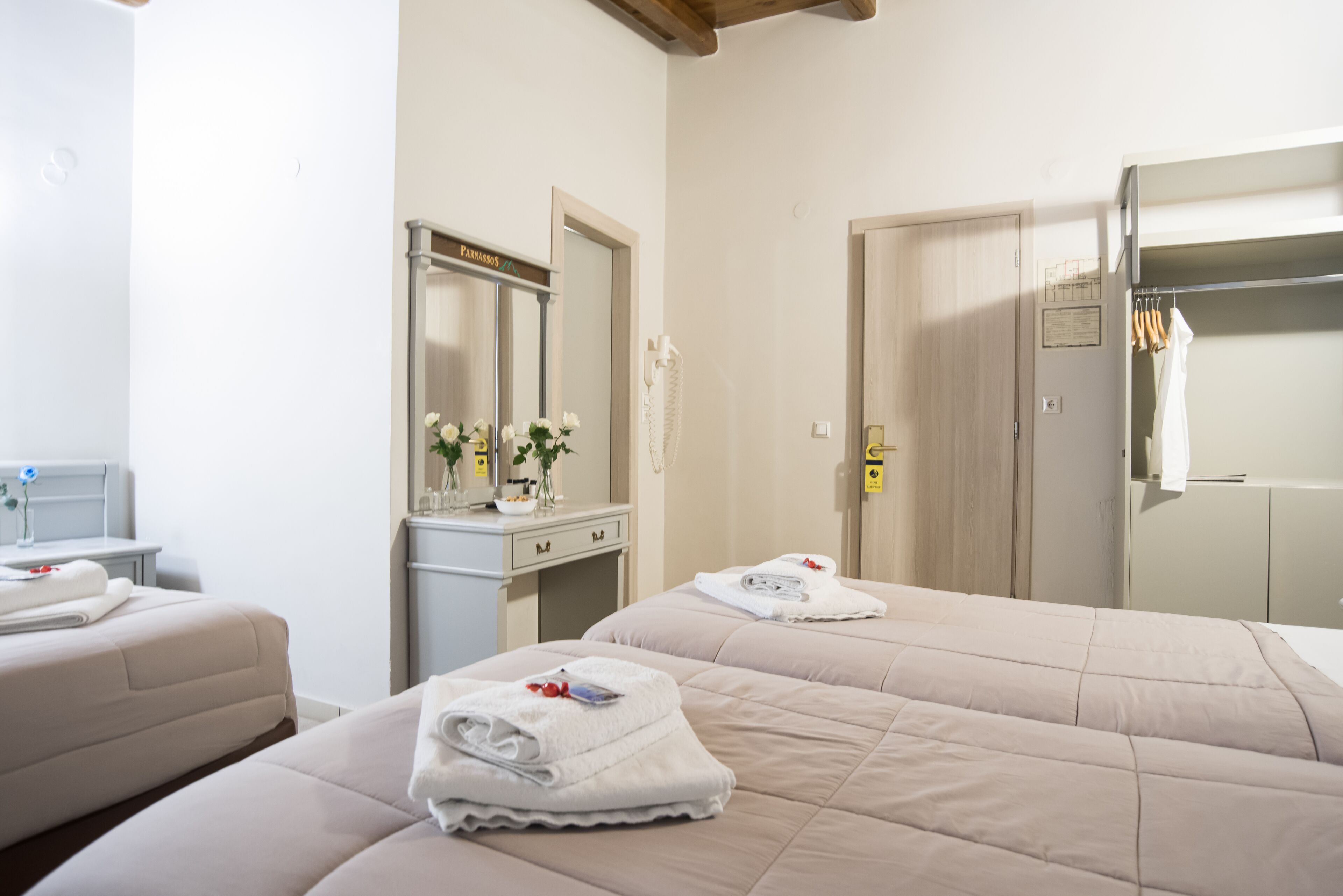 Una habitación de hotel con dos camas, un tocador con espejo y un armario.