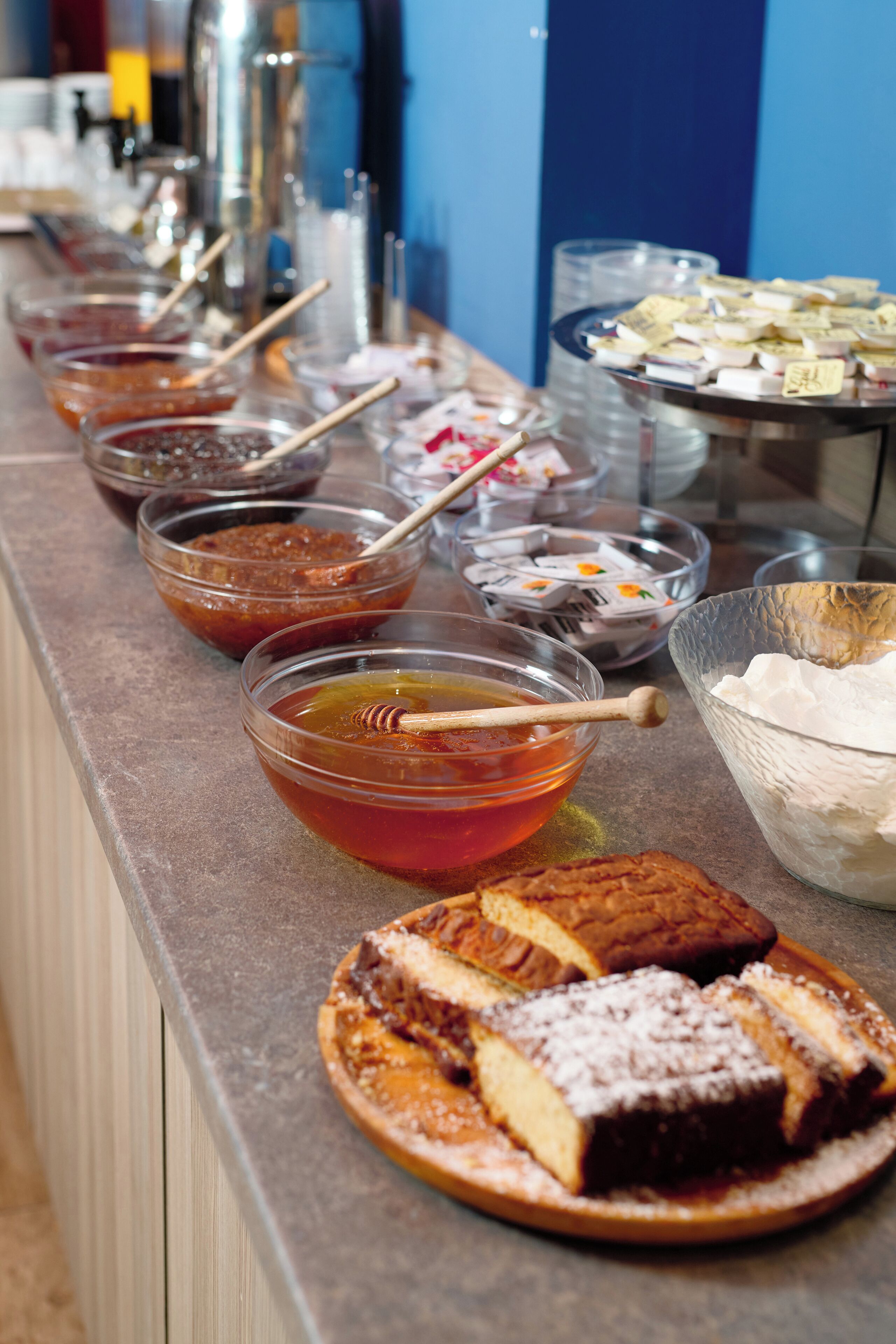 A buffet with various food items including honey, jams, and pastries.