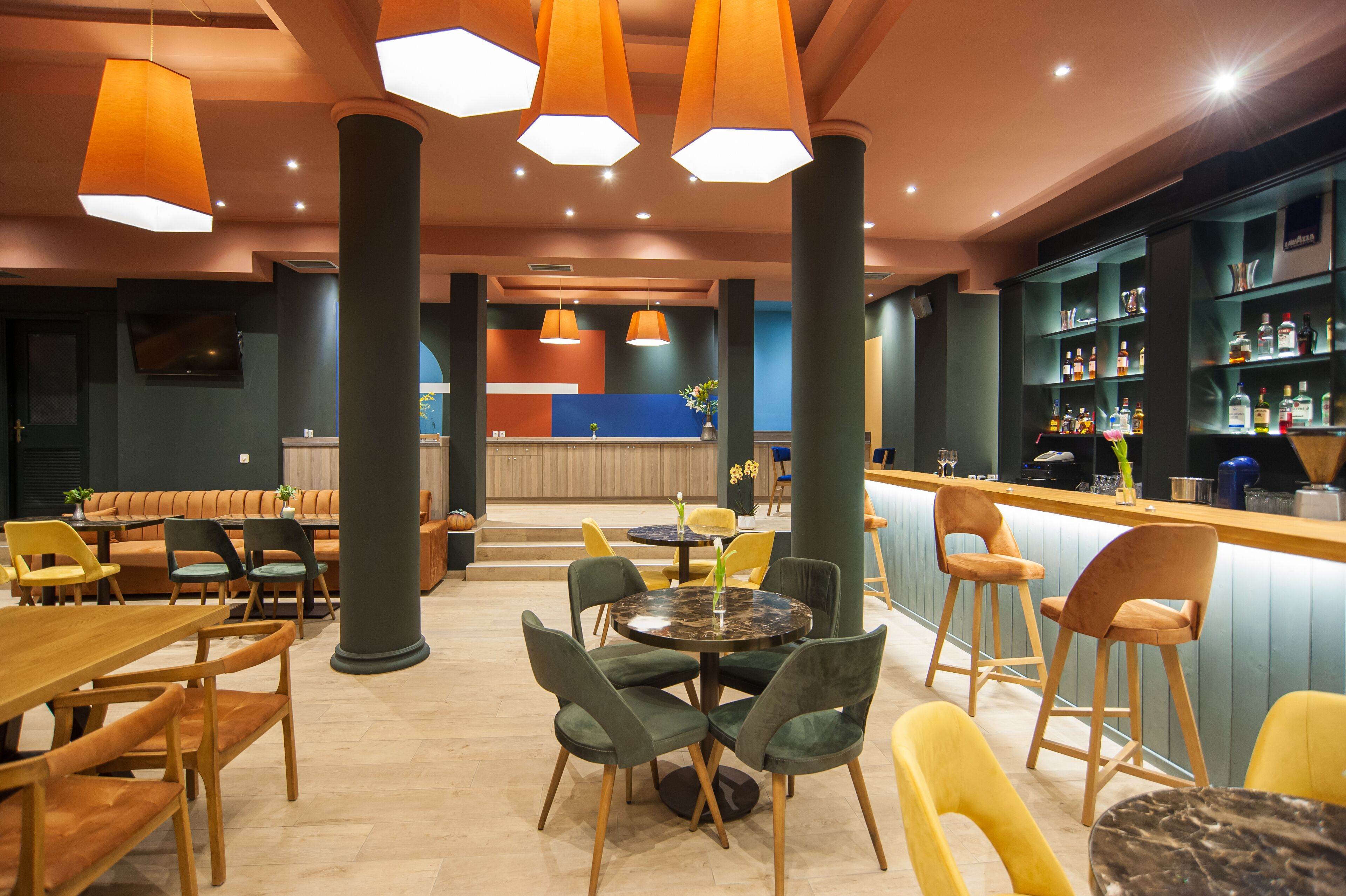 Zona de bar moderna con mesas redondas, taburetes y una variedad de botellas de licor.