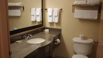 A bathroom with a sink, mirror, towel rack, toilet, and a towel dispenser.