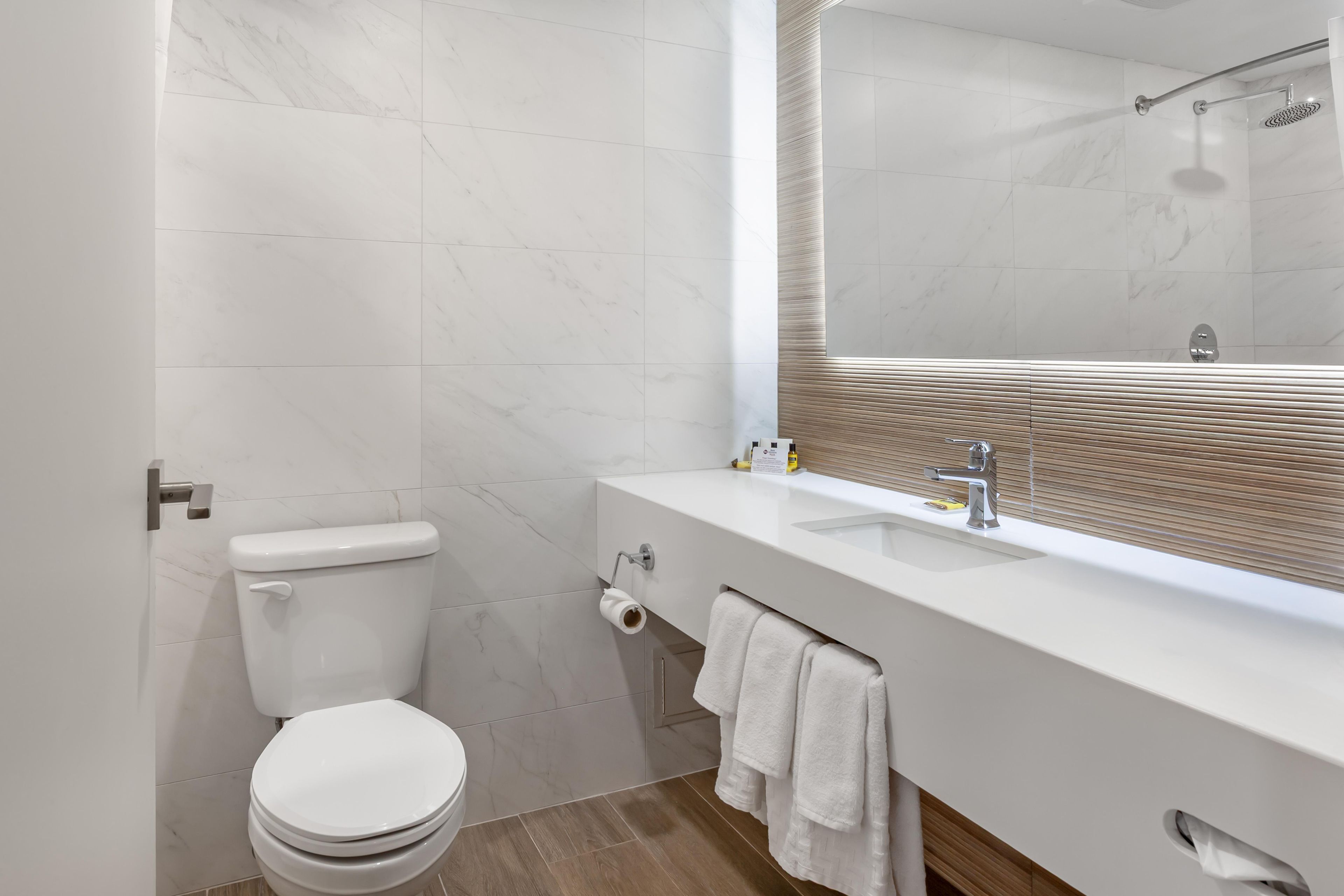 A modern bathroom with a toilet, sink, and mirror.