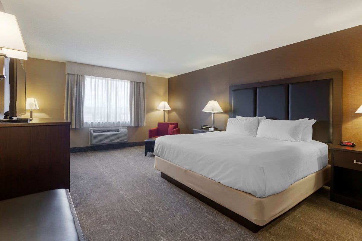 Une chambre d’hôtel avec un grand lit, des lampes de chevet, un bureau et une chaise.