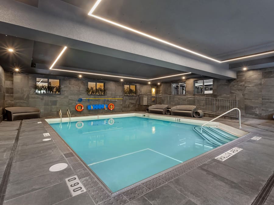 Ein moderner, überdachter Schwimmbereich mit klarem Wasser, Tiefenlinien und Sicherheitsausrüstung.
