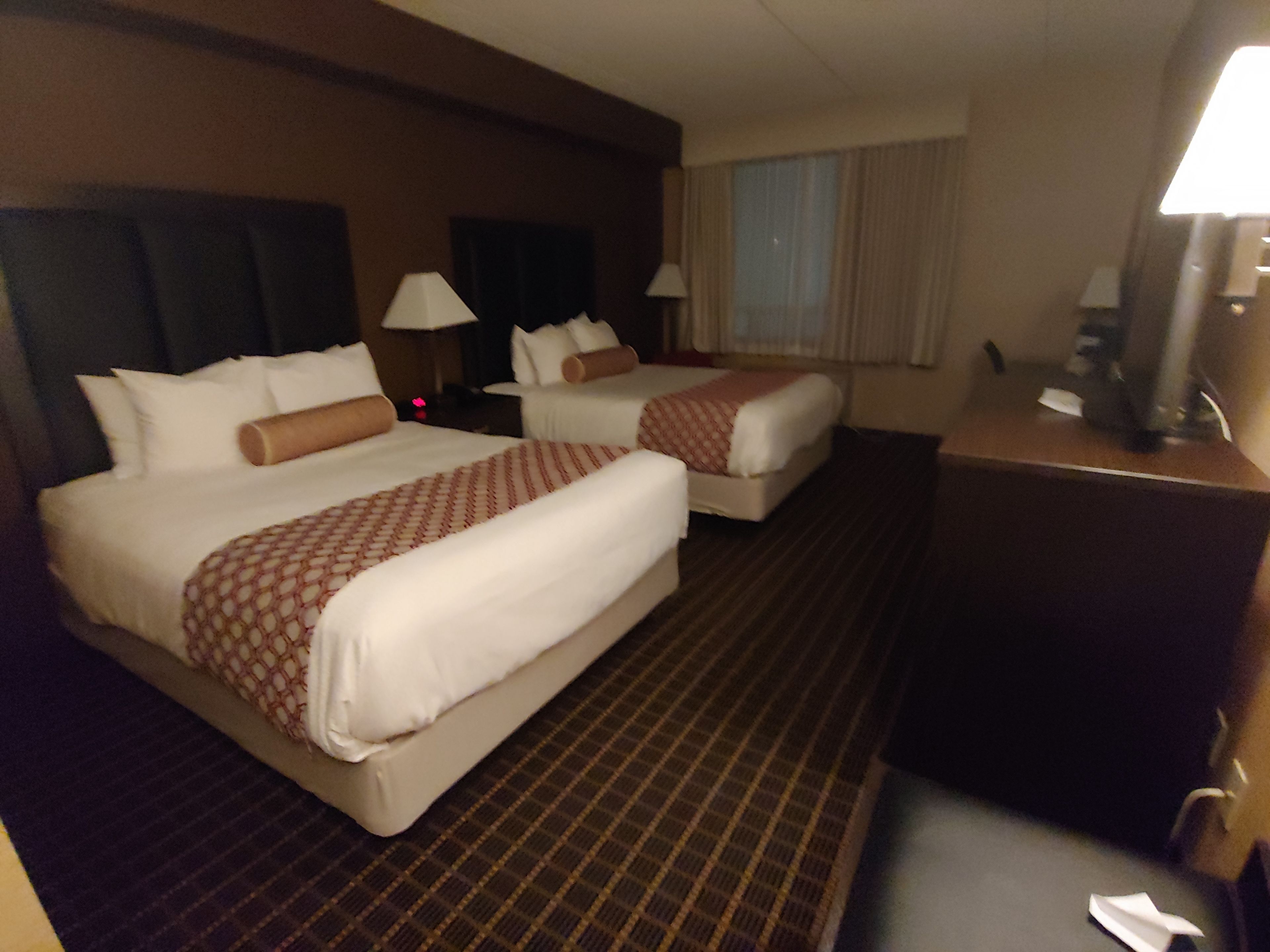 Ein Hotelzimmer mit zwei Betten, einem Schreibtisch und einem Stuhl.