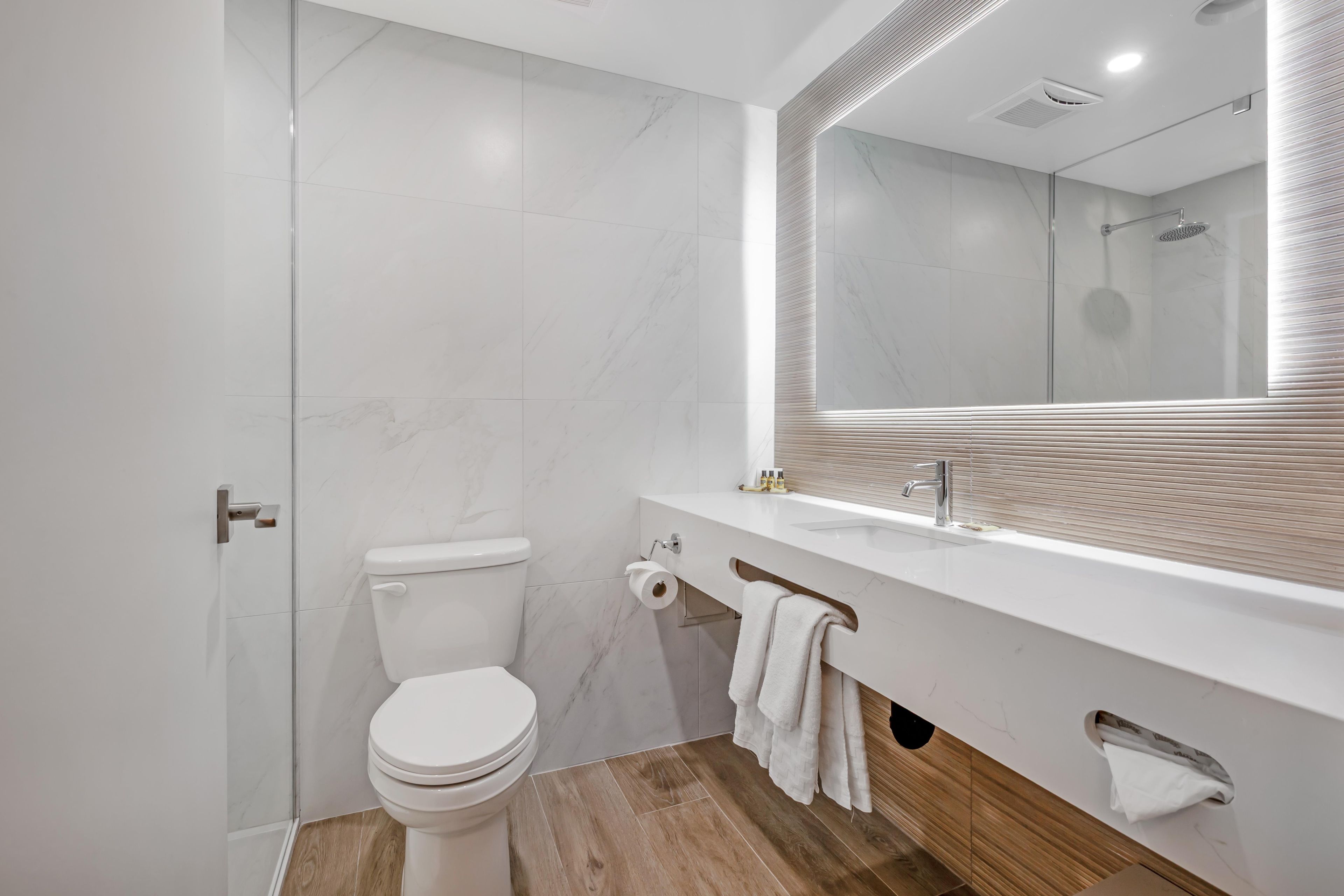 Un baño moderno con inodoro, lavamanos y espejo.