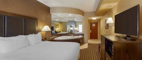 A hotel room with a large bed, a bathroom with a bathtub, a television, and a desk.