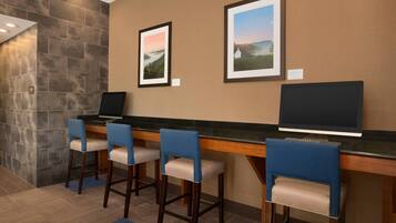 A bar area with a counter, four bar stools, and two framed pictures on the wall.