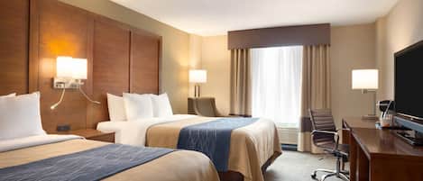 A hotel room with two beds, a desk, a TV, and a chair.