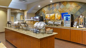 Un espace d’accueil d’hôtel comprenant un comptoir, un buffet et un mur orné d’un motif géométrique.
