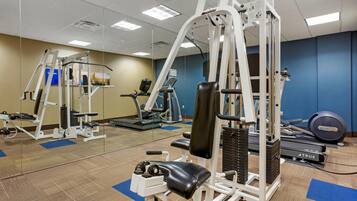 A gym with various exercise equipment, including a leg press machine, a bench press, and a treadmill.