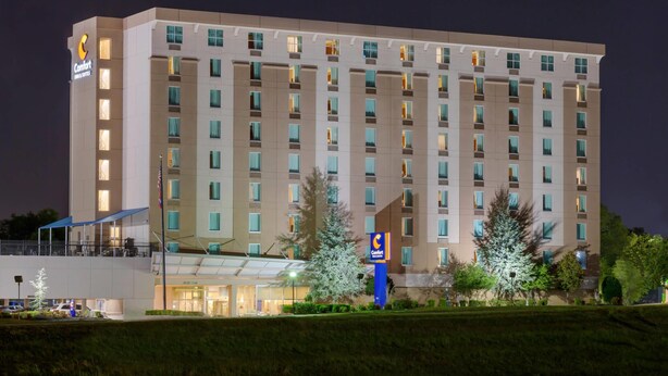 Un hôtel à plusieurs étages, reconnaissable à son grand panneau « Comfort Inn », à son entrée abritée et à sa façade bien éclairée.