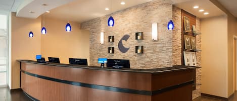 Un mostrador de recepción con un fondo de pared de piedra, varias pantallas de ordenador e iluminación colgante.