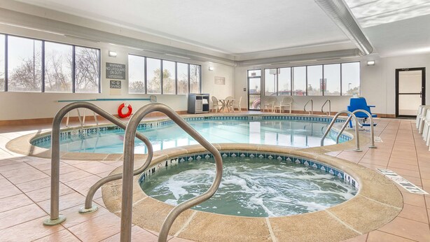 An indoor swimming pool with a hot tub, clear signage, and a view of the outside through large windows. - Comfort Inn Near Six Flags St. Louis (Pacific)