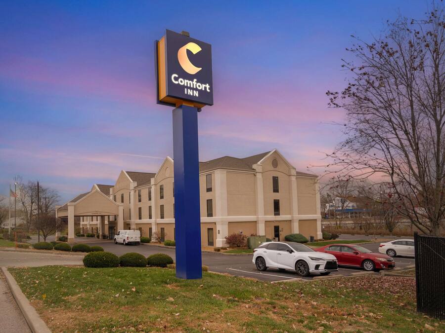 Un hotel Comfort Inn con un cartel llamativo, un estacionamiento con varios coches y un edificio de fachada color crema.