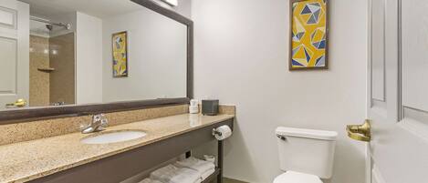 A bathroom with a double sink, a toilet, a towel rack, and a mirror.