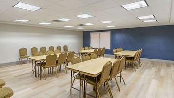 A conference room with multiple tables and chairs, a large window, and a blue accent wall.