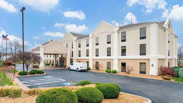 Hotel entrance with covered walkway and neatly manicured grounds.