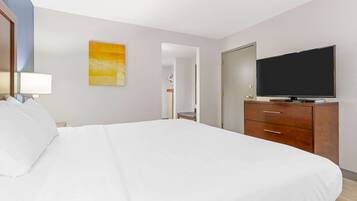 Una habitación de hotel con una cama grande, un televisor sobre una cómoda de madera y un cuadro en la pared.
