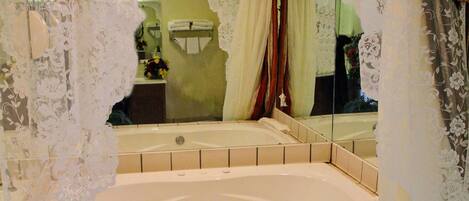 A bathroom with a bathtub, tiled floor, and decorative curtains.