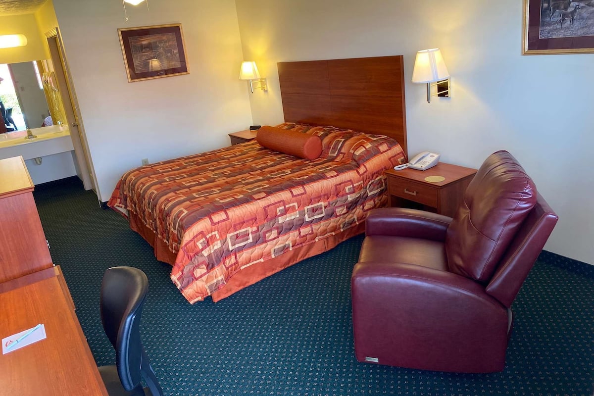 Une chambre d’hôtel avec un lit, un bureau, une chaise et un téléphone.